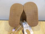 pair of tan slippers with a tag on them sitting on a table