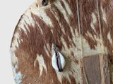 brown and white cowhide purse hanging from a wooden pole