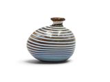 un vase rayé bleu et blanc posé sur une surface blanche