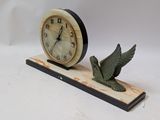 a clock with a bird figurine on a stand