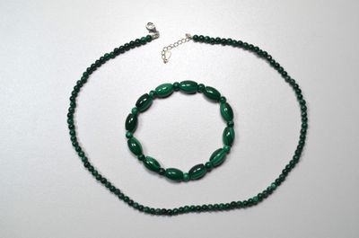 collier et bracelet composés de perles de verre vertes sur un fond blanc