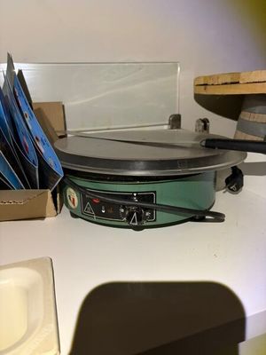 une mijoteuse posée sur un plan de travail, à côté d'une pile de CD