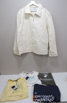 a white shirt on a hanger next to a pile of clothes