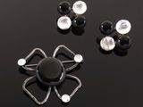 two pairs of black and white earrings on a black surface