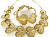 une photo représentant un ensemble composé d'un collier et d'un bracelet en or, posé sur un fond blanc