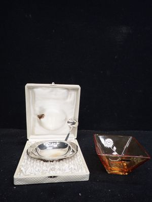 une petite assiette en argent et un bol en verre posés sur une table noire