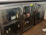 des bouteilles de vin sont posées dans une vitrine en verre dans une cuisine