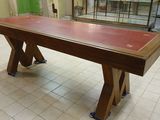 une longue table au plateau rouge dans une pièce