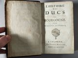 someone is holding an old book in their hand on a table