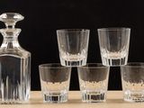 six glasses and a decanter sitting on a table