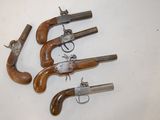 four old guns are lined up on a white surface