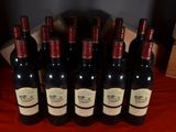 six bottles of wine are lined up on a red table cloth