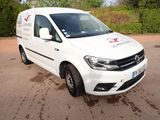 La camionnette blanche est garée sur le parking, près des buissons.