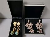 two pairs of earrings are in a black box on a table