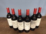 six bottles of red wine lined up on a wooden table