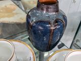 Plusieurs tasses et soucoupes sont exposées dans une vitrine.