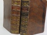 two old books sitting on top of each other on a white surface
