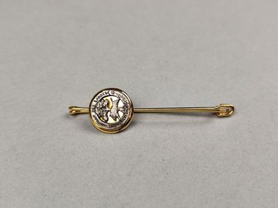 une broche en or sur laquelle est fixée une pièce de monnaie