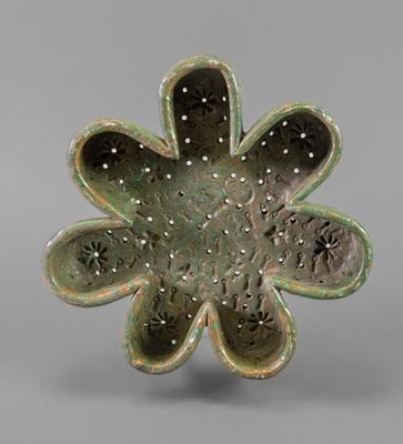 a green flower shaped bowl with holes in the center