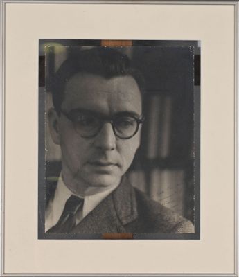 portrait of a man wearing glasses and a suit in a library