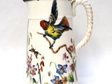 a white pitcher with a bird and flowers on it