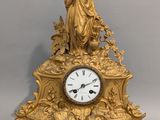 une horloge en or surmontée d'une statue