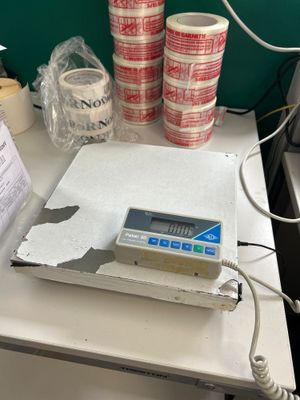 une photo d'une balance posée sur un bureau, recouverte de nombreux morceaux de ruban adhésif