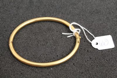 a close up of a gold bracelet with a tag on it