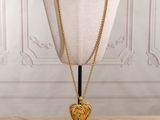 a gold necklace with a heart pendant on a mannequin stand