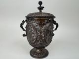 un vase en argent richement décoré, muni d'un couvercle et d'anses, sur fond blanc
