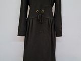 La robe est noire et comporte une boucle dorée à la taille.