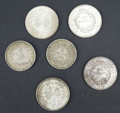 six pièces d'argent sont disposées en cercle sur une surface noire