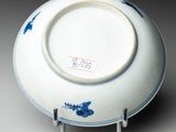 a white plate with blue flowers on it sitting on a stand
