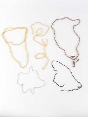 three necklaces with different shapes and sizes on a white surface