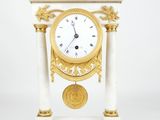 une horloge blanche et dorée posée sur un socle, sur fond blanc