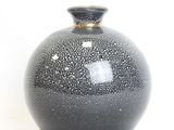 a black and white vase sitting on a white surface