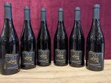 six bottles of wine are lined up on a wooden table