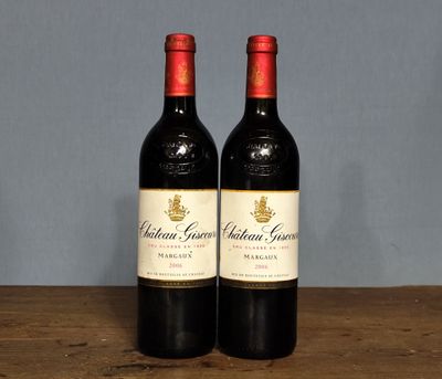 two bottles of red wine sitting on top of a wooden table