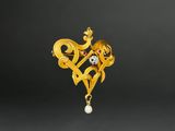 an image of a gold broochle with a heart and a pearl