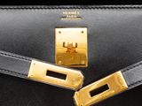 the black and gold hermes bag has a gold buckle on it