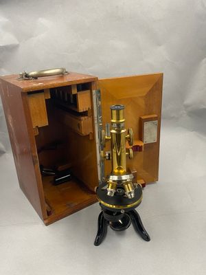une petite boîte en bois contenant un microscope monté sur un trépied