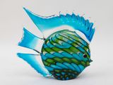 a blue and green glass fish on a white surface