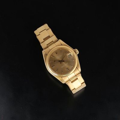 an image of a gold wrist watch on a black surface