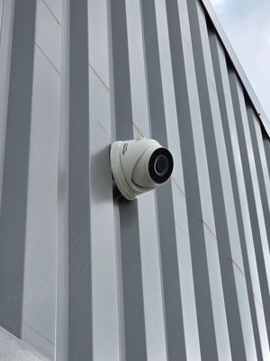 a camera mounted on the side of a building with a sky background