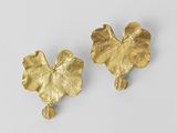 une paire de boucles d'oreilles en feuille d'or sur fond blanc