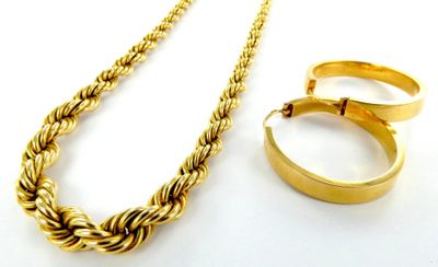 un collier en or et une bague en or posés sur une surface blanche