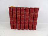 six livres rouges alignés sur une surface blanche