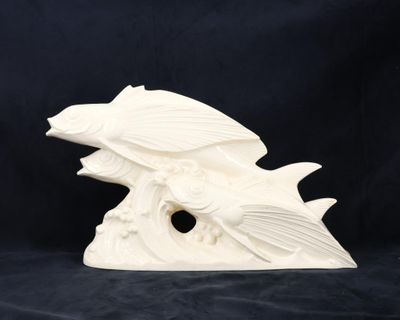 une sculpture en céramique blanche représentant un poisson sur une vague