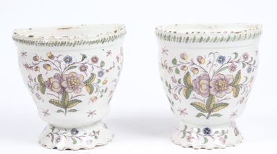two white vases with floral designs on them sitting next to each other