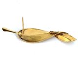 a gold spoon with a leaf on it on a white surface